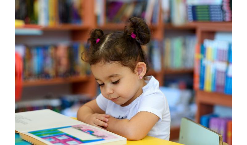 Hispanic Child Reading in Library