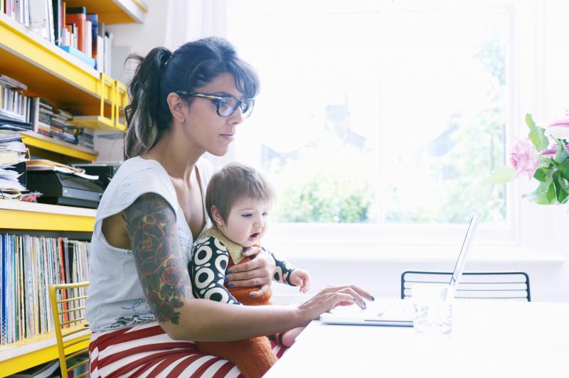 Mother working on laptop with child in lap